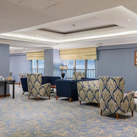 Al Aqeeq Madinah Hotel Medina Exterior foto The photo shows a stylish indoor lounge or sitting area. It features several upholstered armchairs arranged around a central space. The chairs have a blue and cream patterned upholstery, creating a sophisticated ambiance. There is a table alongside s