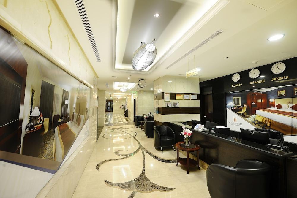 Al Aqeeq Madinah Hotel Medina Exterior foto The photo shows the interior of a hotel lobby or reception area. It features a sleek, modern design with elegant marble flooring, decorative lighting fixtures on the ceiling, and a sophisticated color scheme. There are comfortable black seating areas