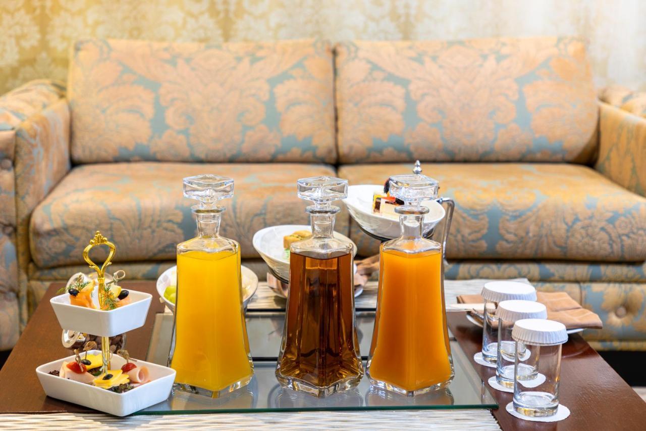Al Aqeeq Madinah Hotel Medina Exterior foto The photo features a beautifully arranged table with several glass decanters filled with liquids. Two decanters, one containing a yellow drink (possibly juice) and another with a darker beverage (possibly tea), are placed prominently. In front of the
