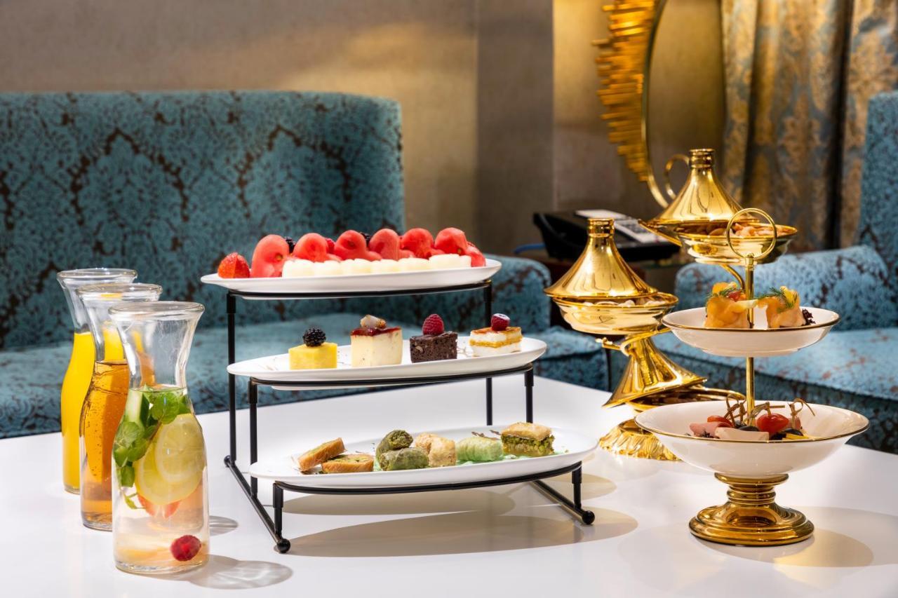 Al Aqeeq Madinah Hotel Medina Exterior foto The photo displays an elegant dessert arrangement on a table. There are two levels of desserts: 

1. **Top Tier**: Features a selection of colorful sweets, including layers of cream or mousse desserts, garnished with fresh berries.
2. **Bottom Tier**